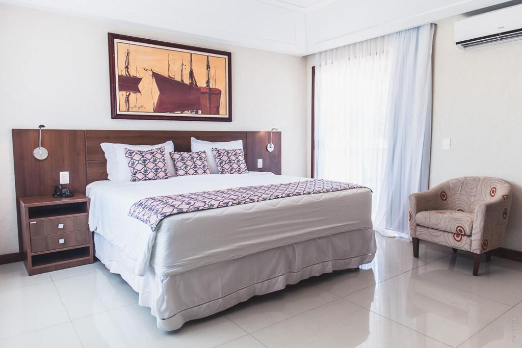 Quarto do Hotel Ferradura Resort, em Búzios, com cama de casal, poltrona e decoração náutica.
