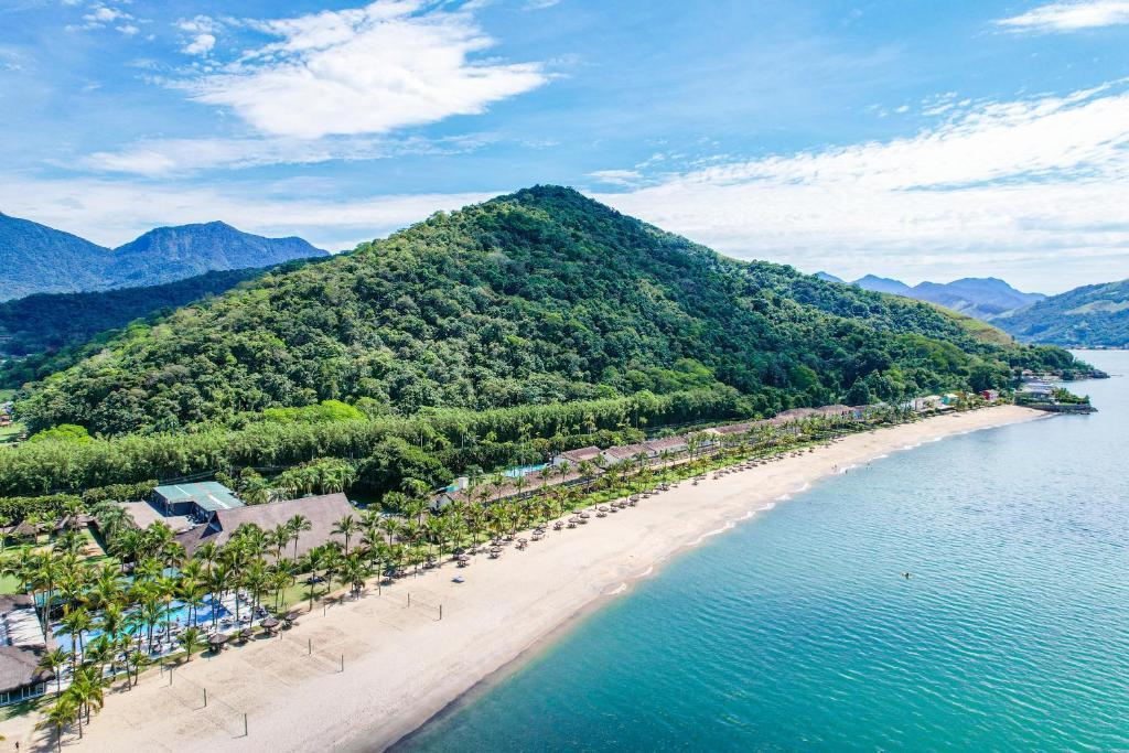 Vista aérea do Hotel Portobello Resort & Safari, em Mangaratiba, entre a praia e montanhas cobertas por mata.