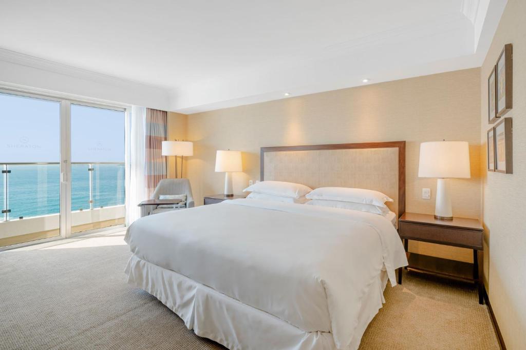 Quarto do Sheraton Grand Rio Hotel & Resort, no Rio de Janeiro, com cama ampla e varanda de frente para o mar.