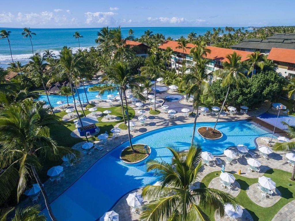 Área de piscinas do Porto Beach Resort Marulhos, em Porto de Galinhas, com coqueiros e vista para o mar