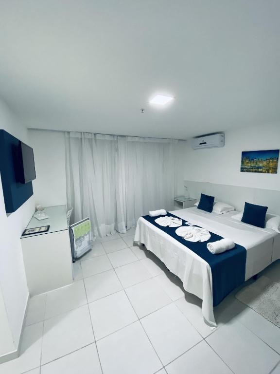 Quarto do Hotel Real, em Cabo Frio, com cama de casal, decoração branca e detalhes em azul