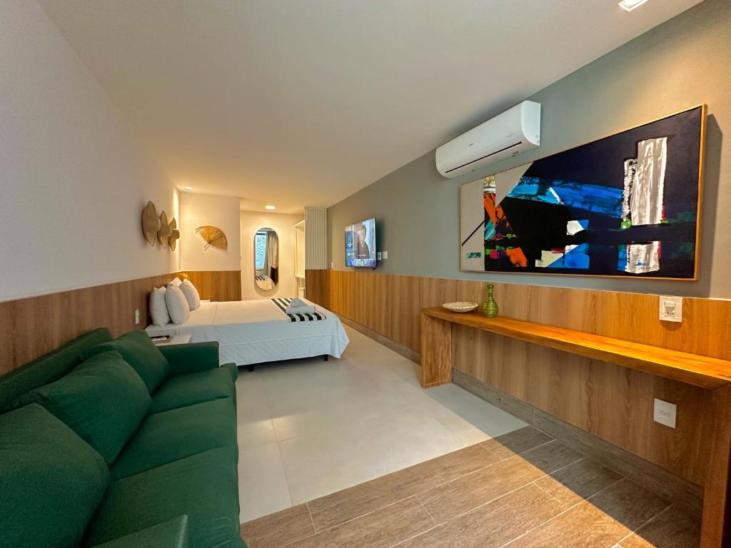 Suíte do Passagem Concept Hotel e Spa, em Cabo Frio, com cama, sofá verde e bancada de madeira