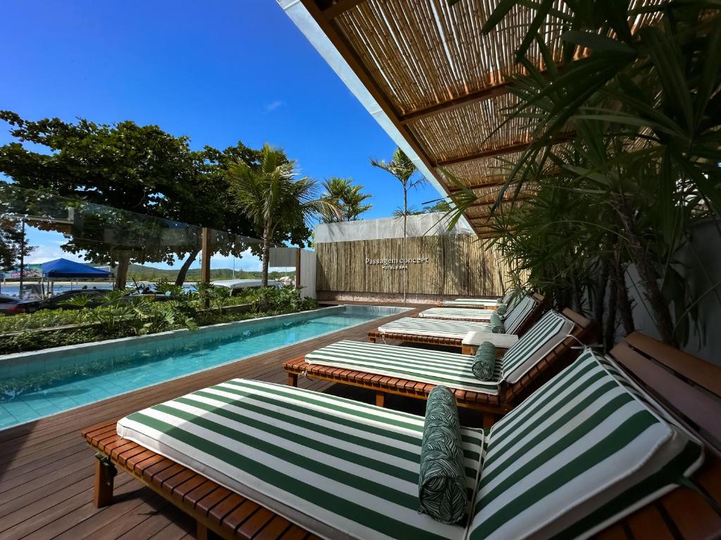 Área externa do Passagem Concept Hotel e Spa, em Cabo Frio, com piscina estreita e espreguiçadeiras listradas