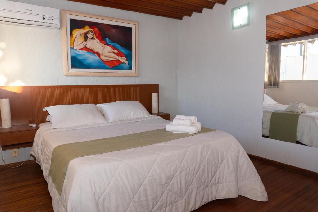 Quarto da Pousada Marília, em Cabo Frio, com cama de casal, piso de madeira e espelho grande