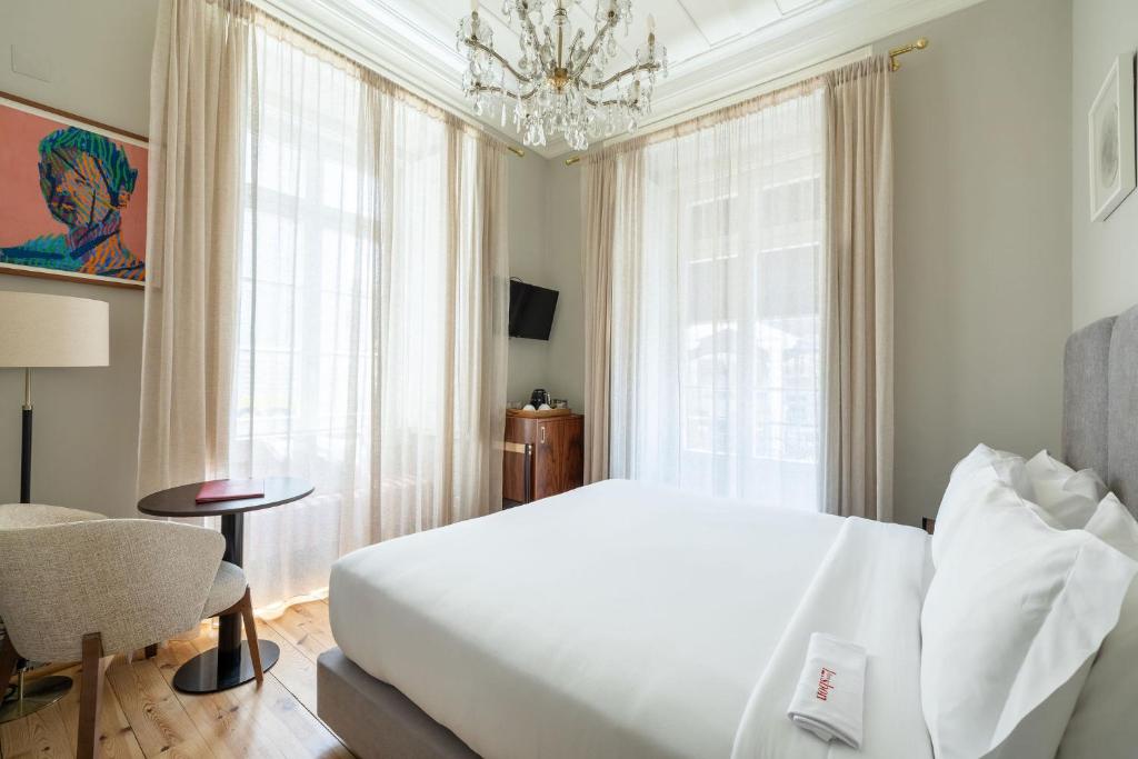 Quarto do Dare Lisbon River, em Lisboa, com cama de casal, lustre de cristal e janelas amplas.