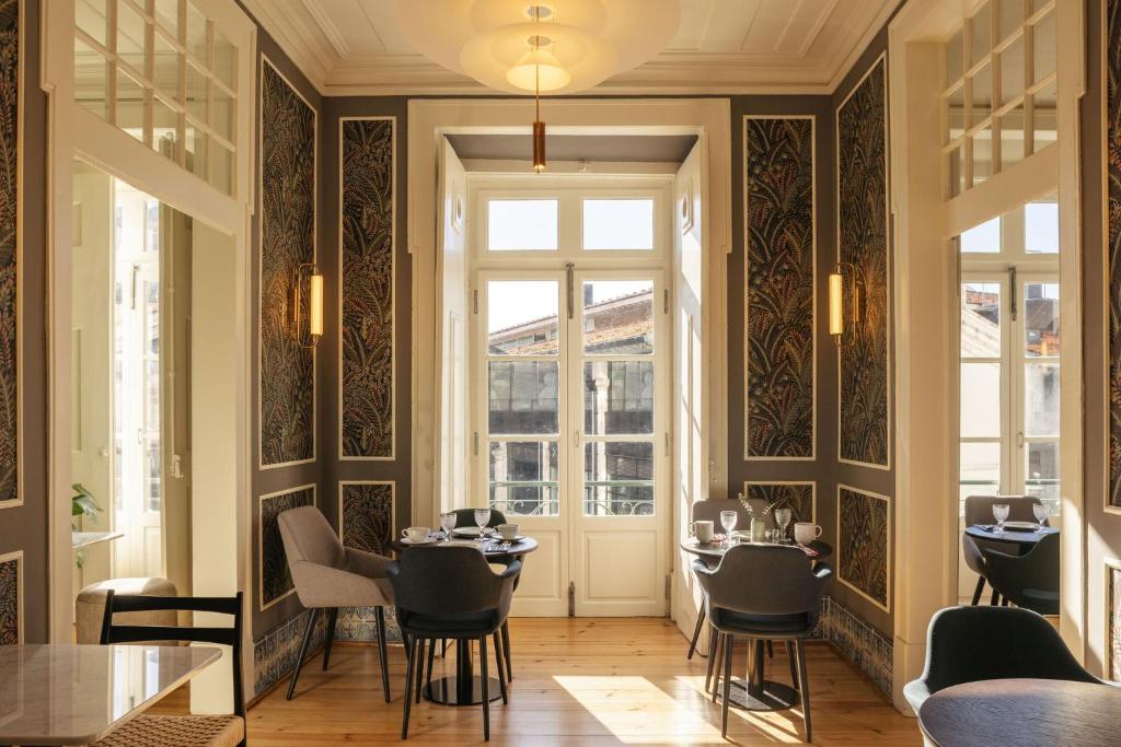 Sala de refeições do Dare Lisbon River, em Lisboa, com decoração elegante, mesas e grandes janelas.