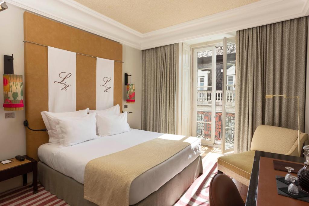 Quarto do Heritage Avenida Liberdade, em Lisboa, com cama de casal e portas abertas para uma varanda.