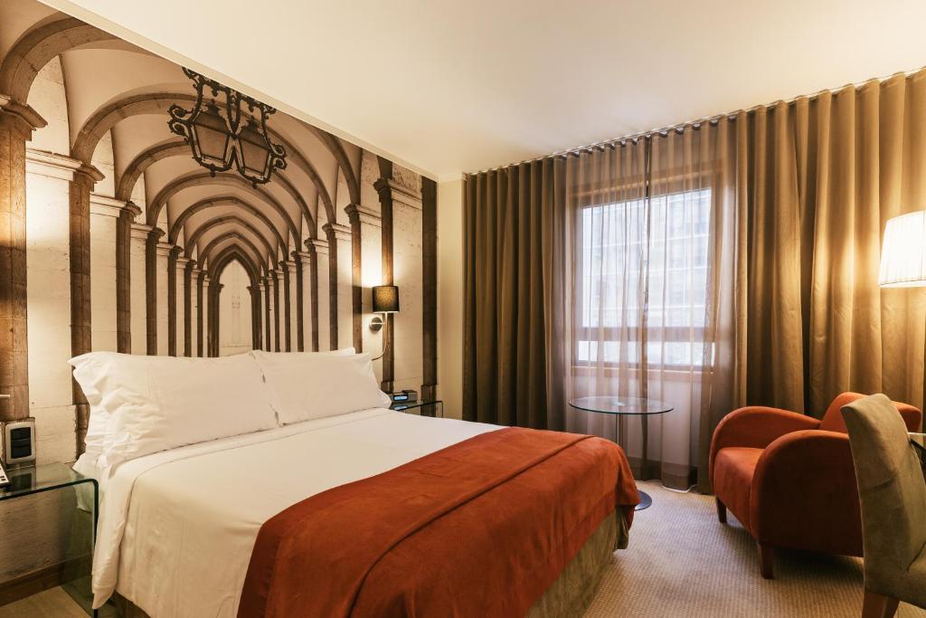 Quarto do Hotel Marquês de Pombal, em Lisboa, com cama de casal, manta vermelha e decoração em tons quentes.