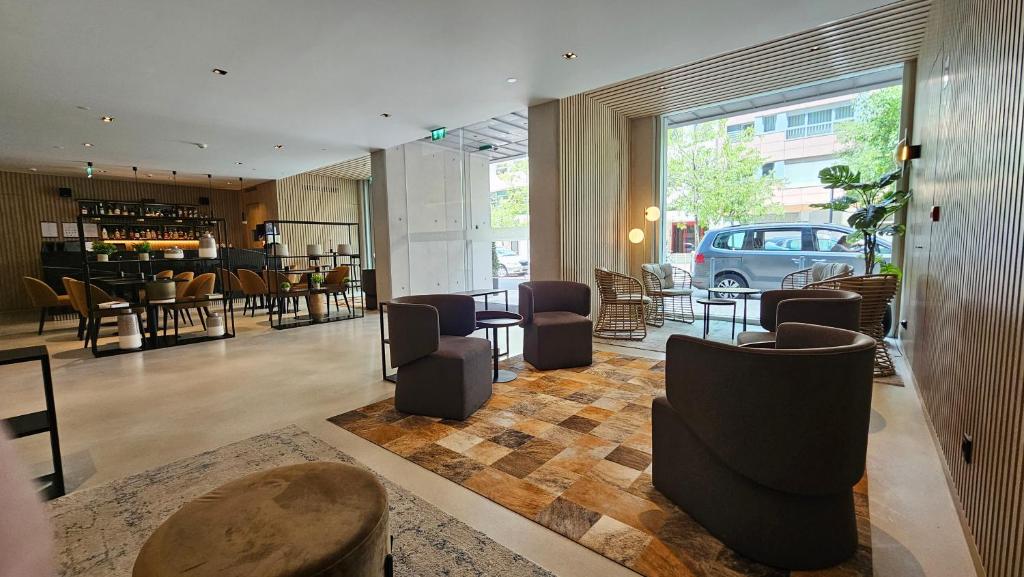 Lobby do Hotel Principe Avila, em Lisboa, com poltronas, mesas e grandes janelas voltadas para a rua.