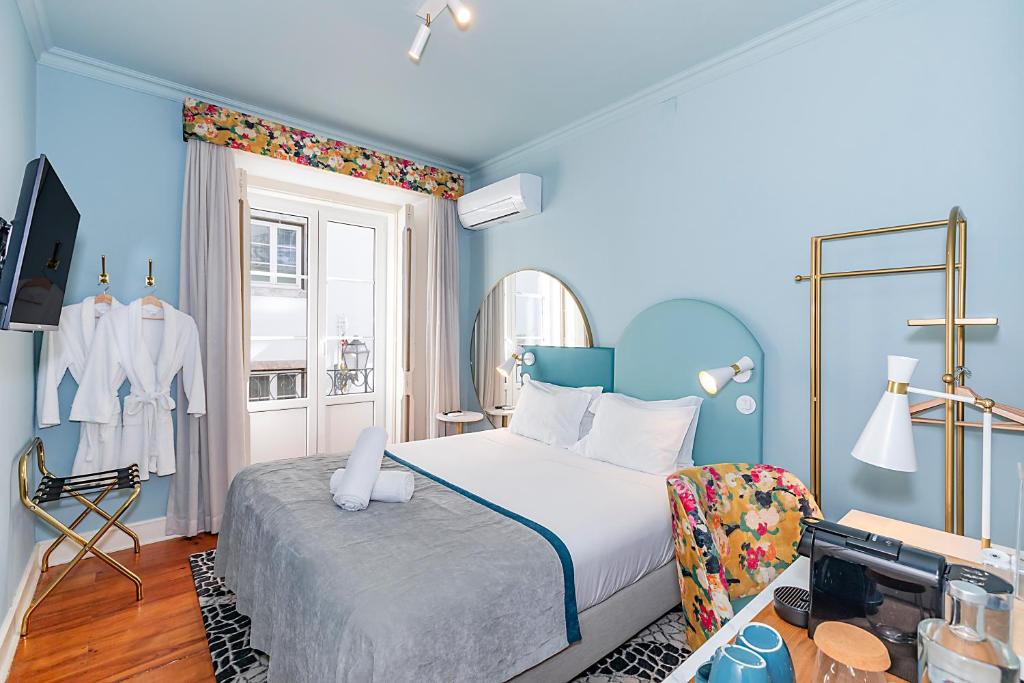 Quarto do LR Guest House, em Lisboa, com cama de casal, paredes azuis e detalhes florais.