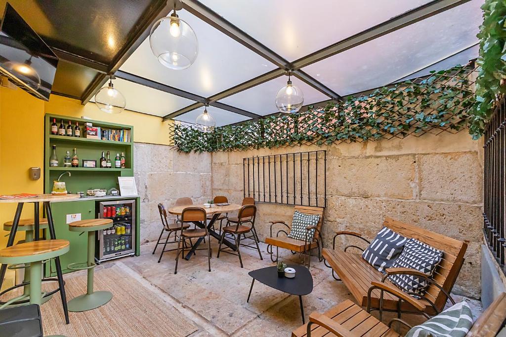 Pátio do LR Guest House, em Lisboa, com mesas, bancos de madeira e pequeno bar coberto.