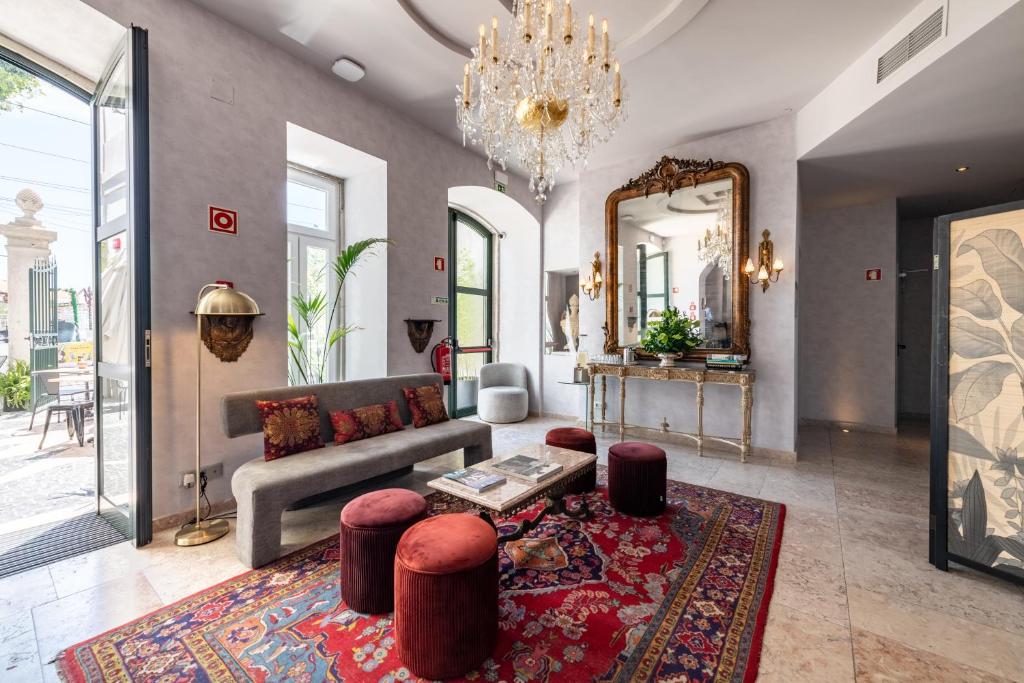 Área de estar da Pousada Alfama, em Lisboa, com lustre de cristal, sofá e decoração clássica.