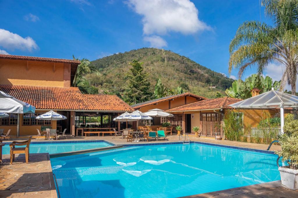 Piscina do Bomtempo Itaipava Hotel by Castelo Itaipava, em Petrópolis, com montanhas ao fundo.