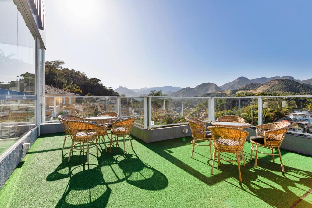Terraço do Hotel Petrópolis Inn, em Petrópolis, com mesas e vista para as montanhas.