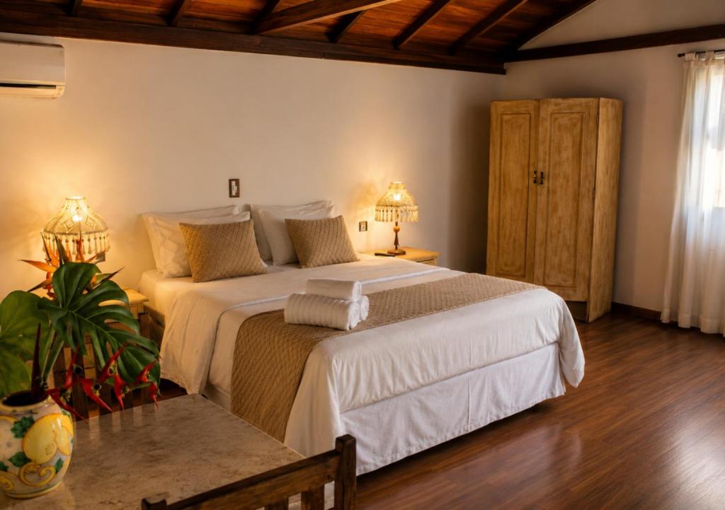 Quarto do Kastel Pedra Bonita, em Petrópolis, com cama de casal, decoração em tons claros e piso de madeira.