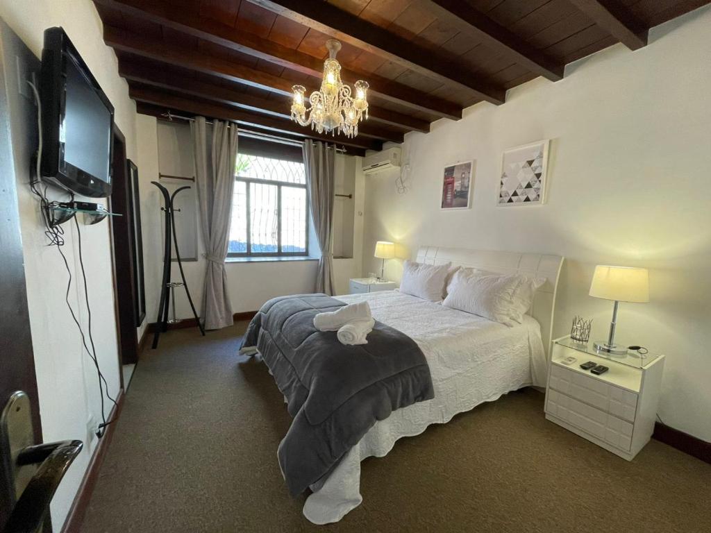 Quarto da Pousada Cozy Home, em Petrópolis, com cama de casal, lustre de cristal e decoração clássica.