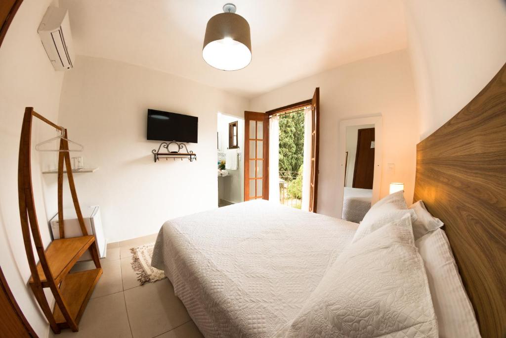 Quarto da Pousada do Lago, em Petrópolis, com cama de casal, varanda e decoração clara.