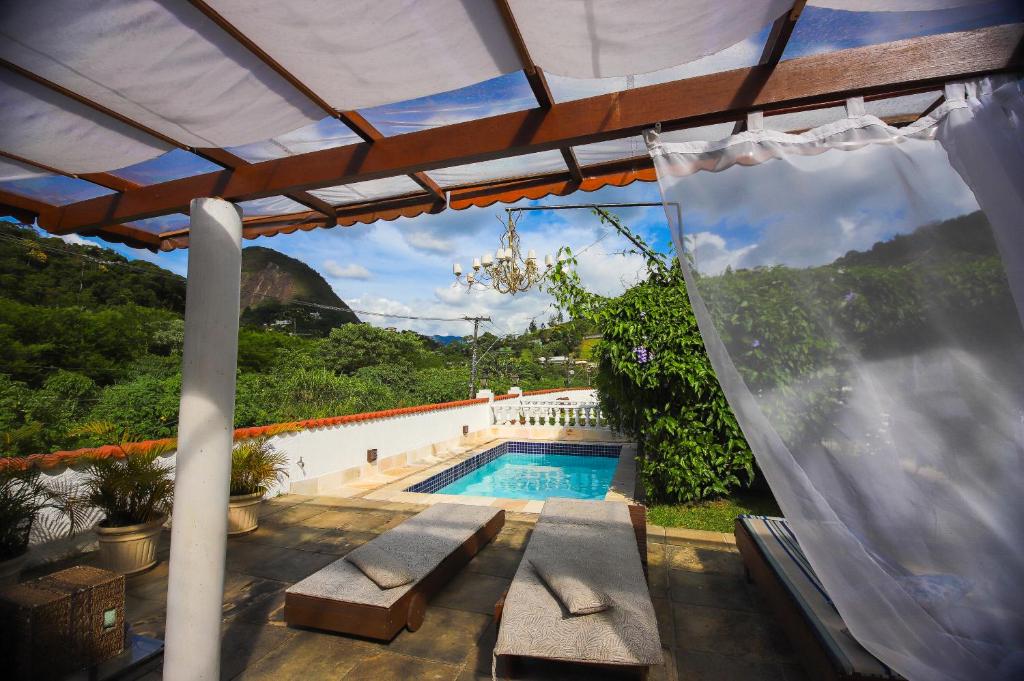 Piscina da Pousada do Lago, em Petrópolis, com espreguiçadeiras e vista para as montanhas.