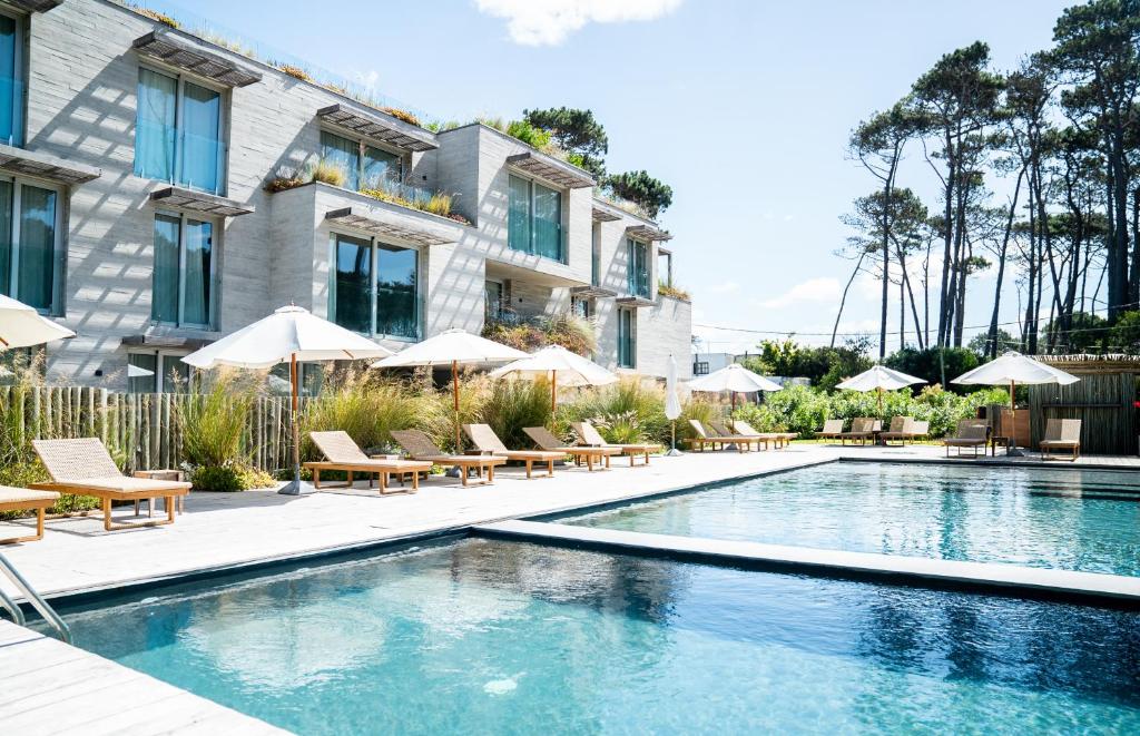 Piscinas e área externa do Casagrande Hotel & Beach Club, em Punta del Este, com espreguiçadeiras e edifício ao fundo.