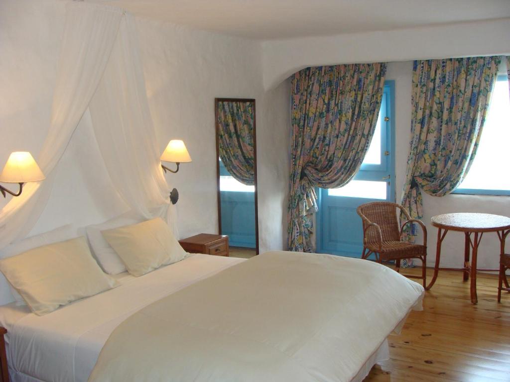 Quarto do Club Hotel Casapueblo, em Punta del Este, com cama de casal e portas azuis junto às janelas.