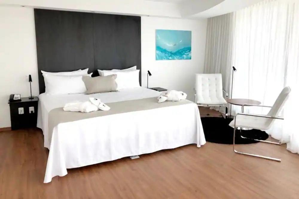 Quarto do Don Hotel, em Punta del Este, com cama ampla, poltronas e decoração contemporânea.
