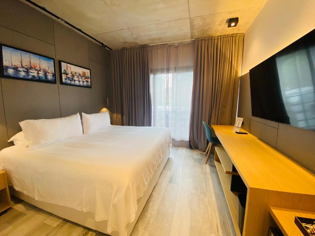 Quarto do La Capilla Punta del Este, com cama de casal, televisão e decoração em tons neutros.