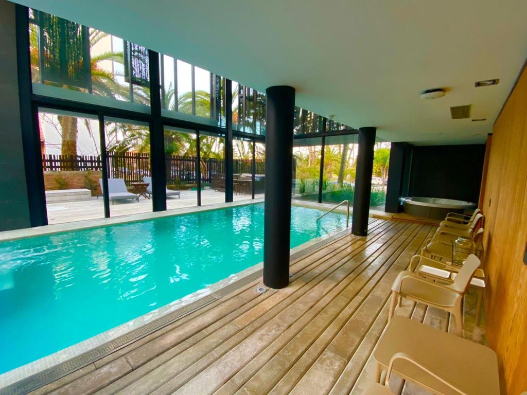Piscina coberta do La Capilla Punta del Este, com espreguiçadeiras e grandes janelas voltadas para o jardim.