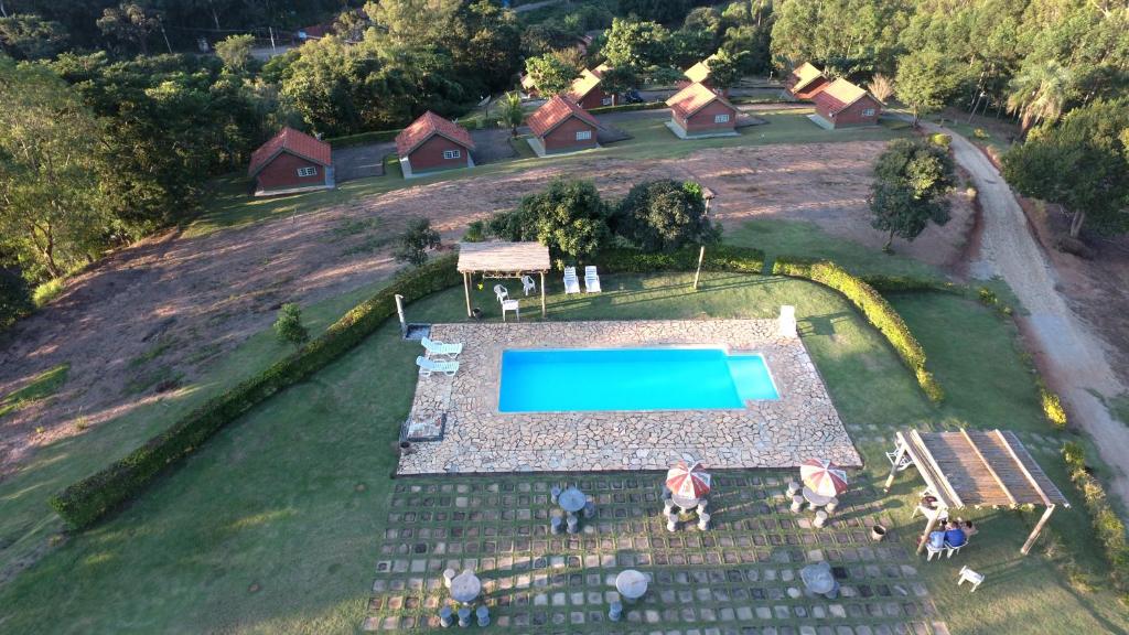 Vista aérea da Pousada Ecológica Rio do Peixe, em Socorro, com piscina, área gramada e chalés cercados por árvores.
