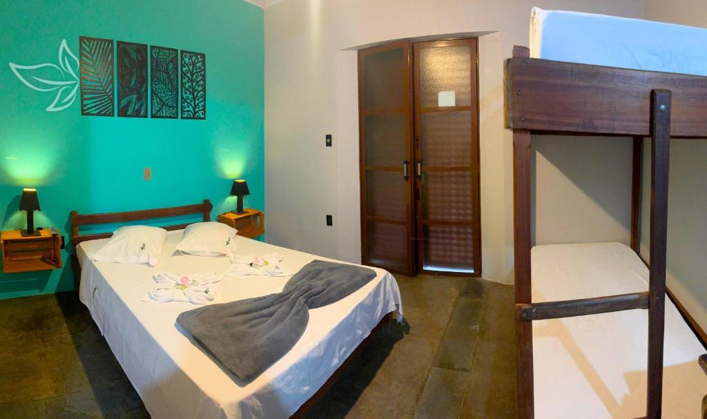 Quarto da Pousada Nativa, em Socorro, com cama de casal, beliche e parede verde decorada.