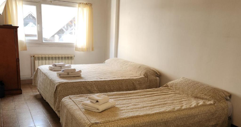 Quarto do Anum Hostel, em Ushuaia, com duas camas, toalhas dobradas e janela ampla.