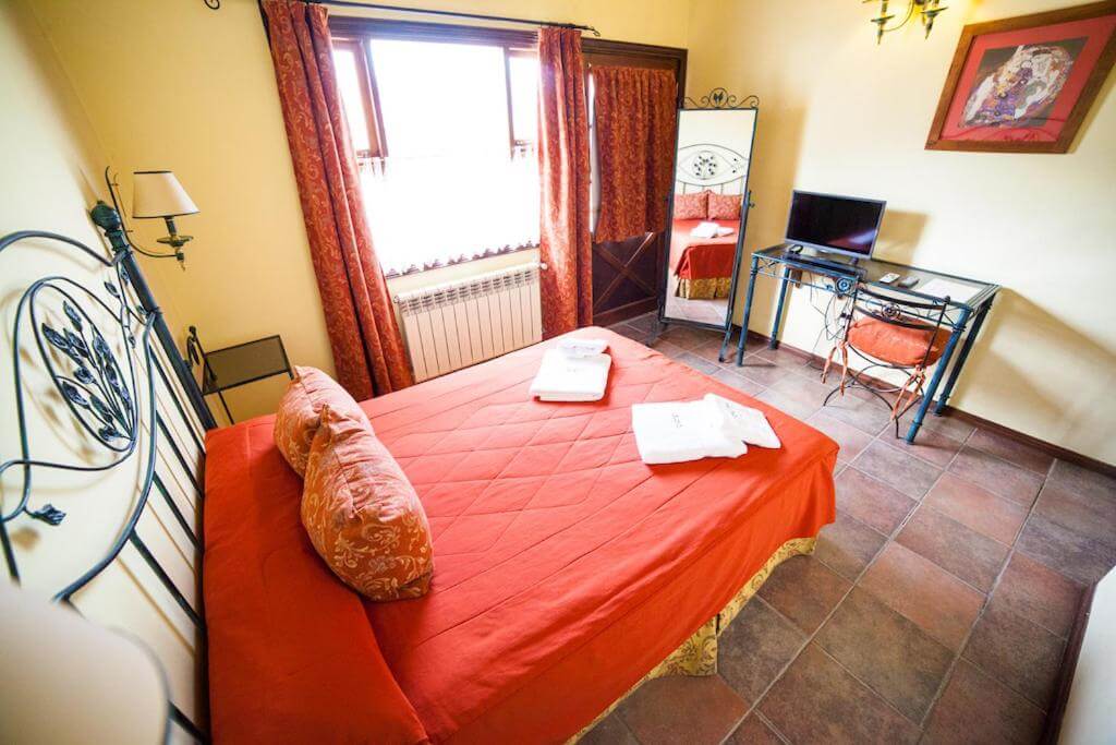 Quarto do Hotel Campanilla, em Ushuaia, com cama de casal, decoração em tons quentes e janela.