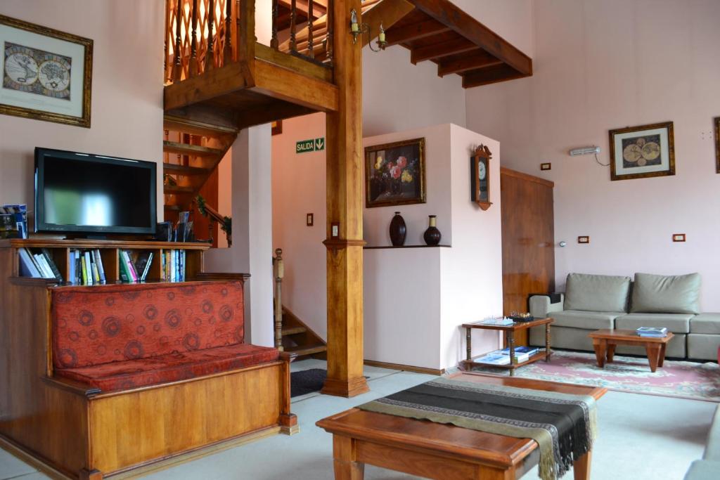 Sala do Valle Frío Ushuaia, em Ushuaia, com móveis de madeira, sofás e escada para o piso superior.