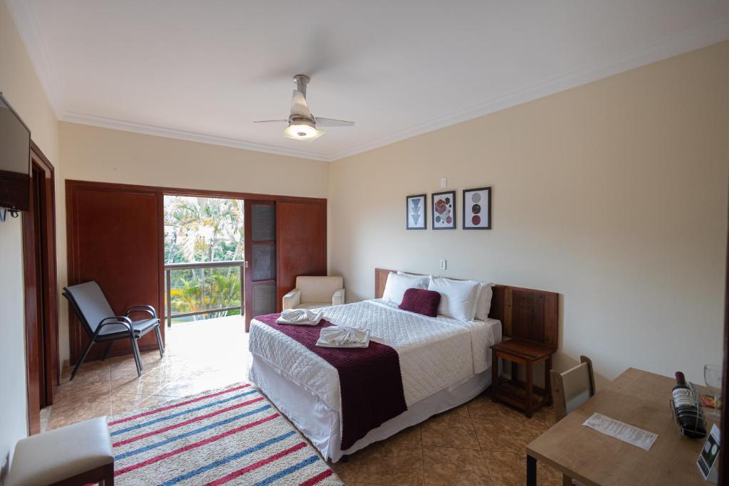 Quarto da Pousada Costa Rielli, em Águas de Lindóia, com cama de casal e varanda voltada para o verde.