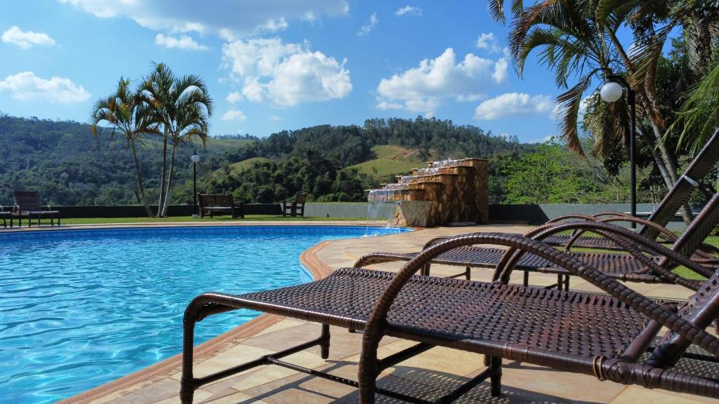 Piscina da Pousada Costa Rielli, em Águas de Lindóia, com espreguiçadeiras e vista para as montanhas.