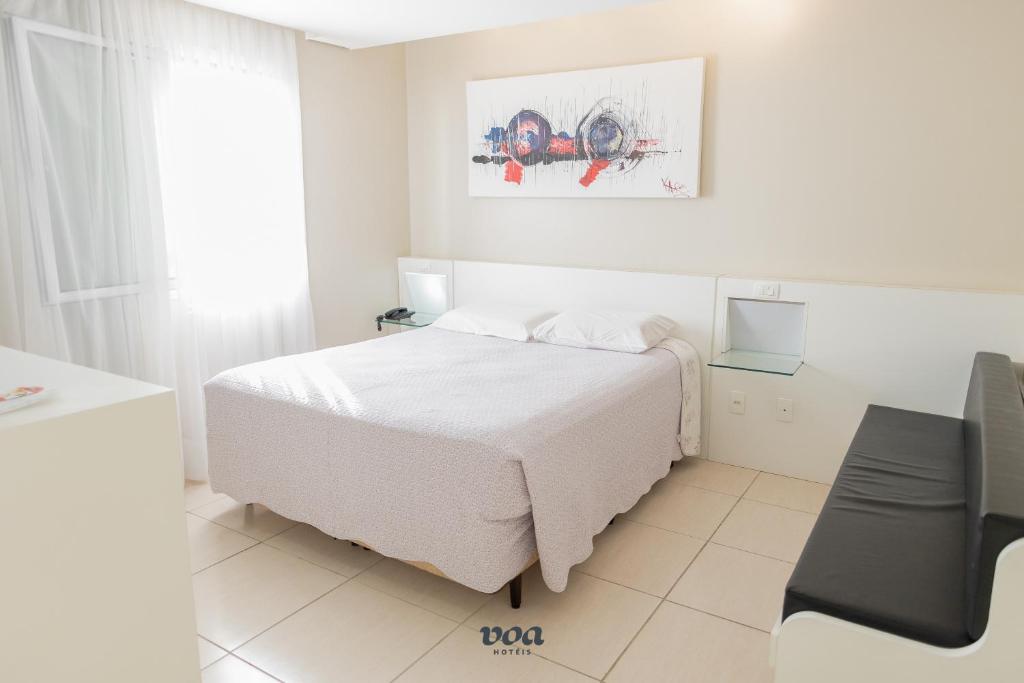 Quarto do VOA Plazza Hotel, em Águas de Lindóia, com cama de casal, decoração clara e sofá.