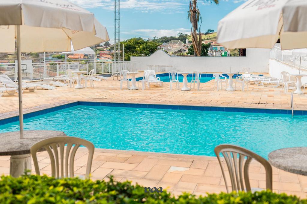 Área de piscinas do VOA Plazza Hotel, em Águas de Lindóia, com mesas, espreguiçadeiras e guarda-sóis.