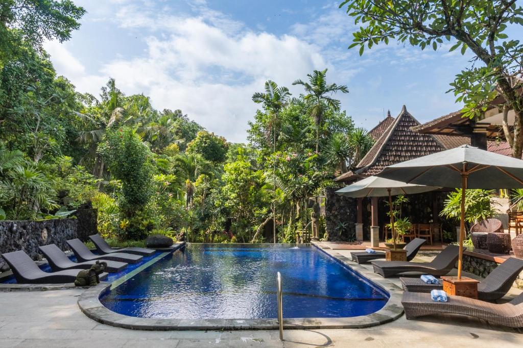 Piscina do Dewangga Ubud, em Bali, cercada por jardim tropical e espreguiçadeiras