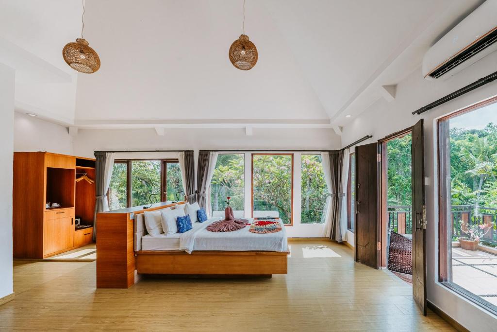 Quarto do Dewangga Ubud, em Bali, com cama de casal, janelas grandes e vista para área verde