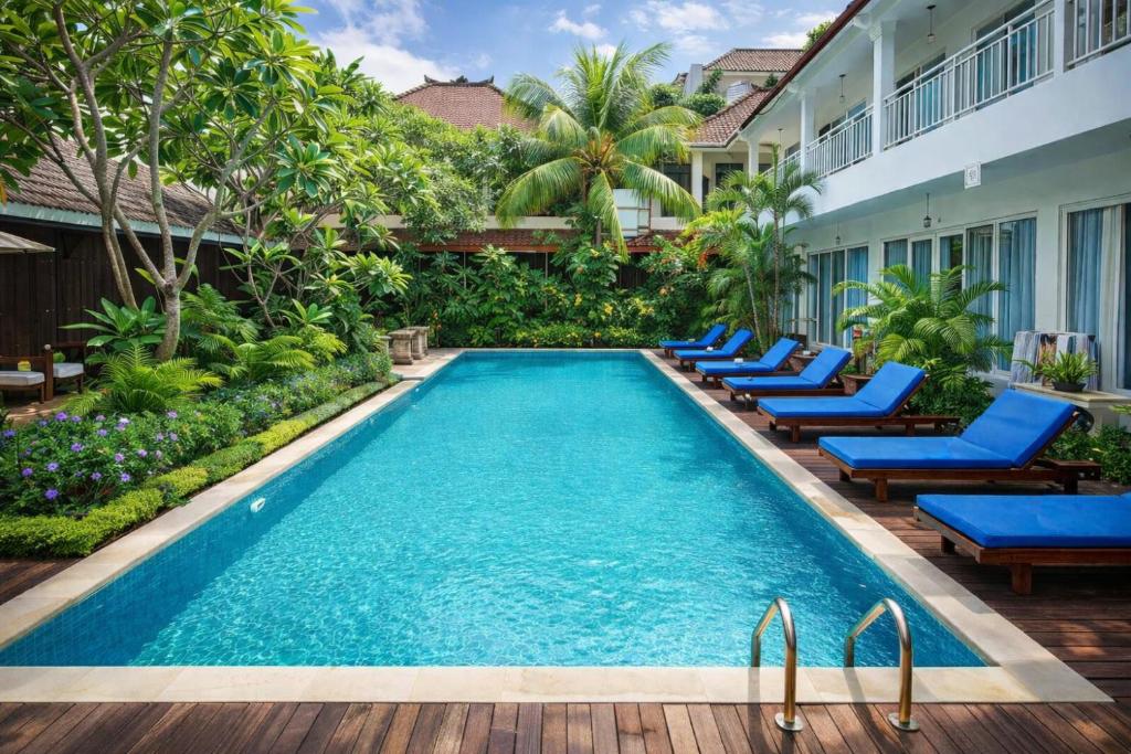 Piscina do Easy Surf Camp, em Bali, com espreguiçadeiras azuis e jardim ao redor