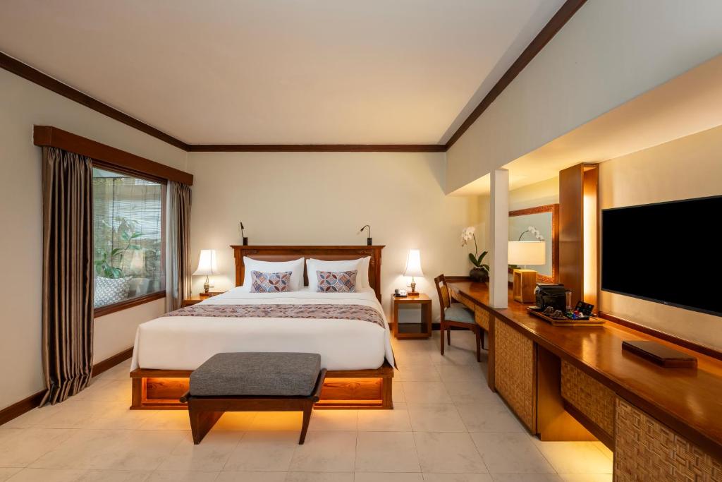 Quarto do Kuta Seaview Beach Resort, em Bali, com cama de casal, mesa de trabalho e móveis de madeira
