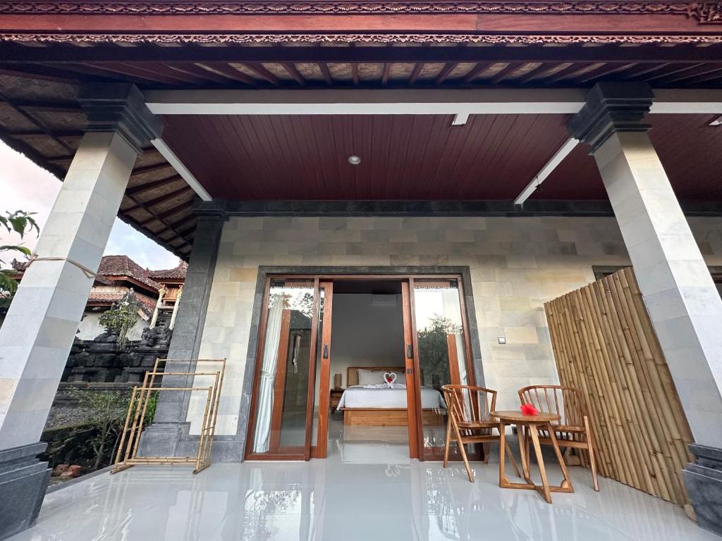 Varanda do Made Putu Homestay, em Bali, com portas de vidro, mesa com cadeiras e quarto ao fundo
