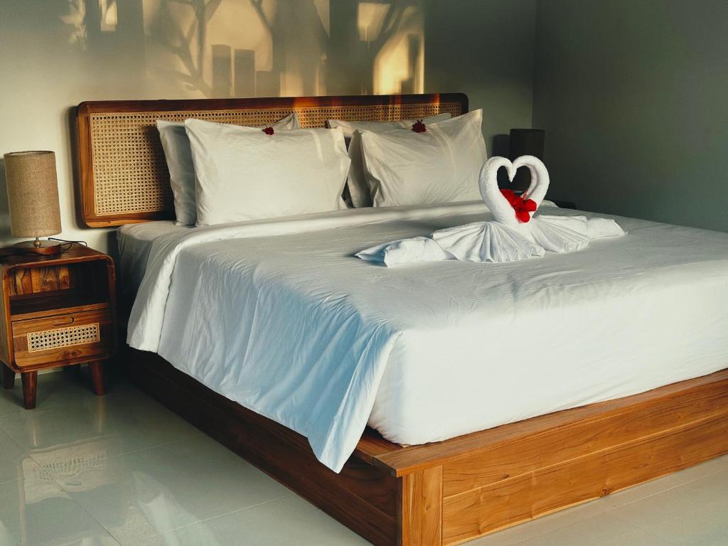 Quarto do Made Putu Homestay, em Bali, com cama de casal de madeira e toalhas em formato de cisne