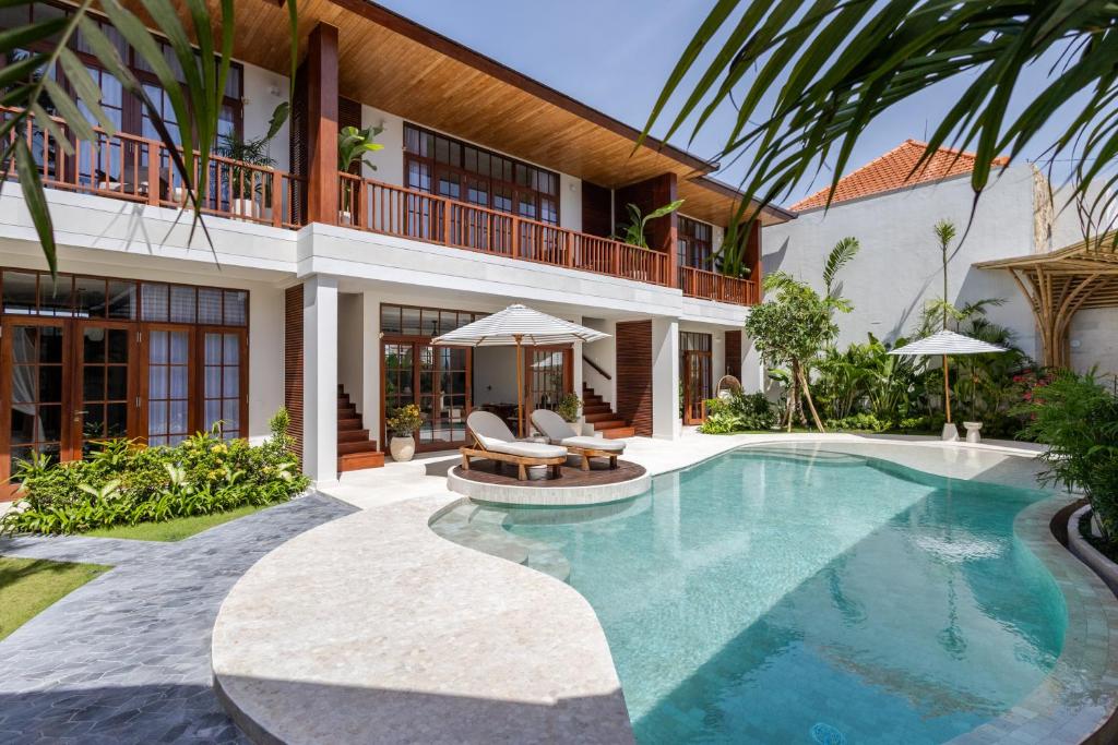 Piscina de hotel com espreguiçadeiras, guarda-sóis e prédio de dois andares com varandas de madeira