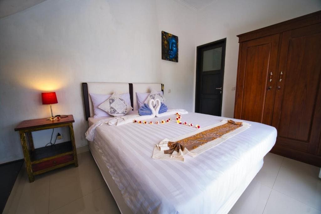 Quarto do Sing Sing Resort Lovina, em Bali, com cama de casal, armário de madeira e decoração com floresa
