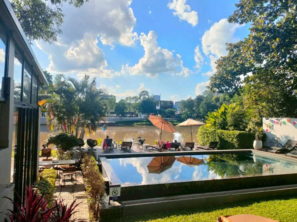 Piscina de hotel com vista para o rio sob céu ensolarado em Chiang Mai.