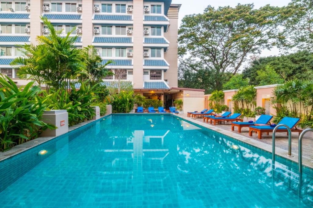 Piscina de hotel ao ar livre com água azul turquesa e espreguiçadeiras em Chiang Mai.