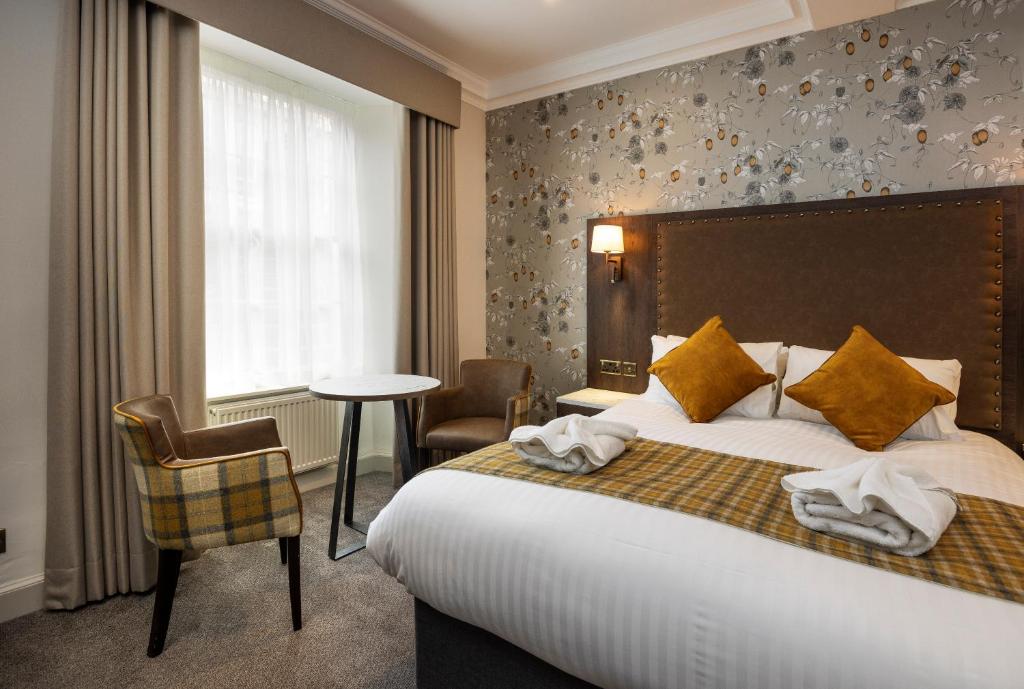Cama de casal com almofadas mostarda e papel de parede floral aconchegante no Albany Hotel.