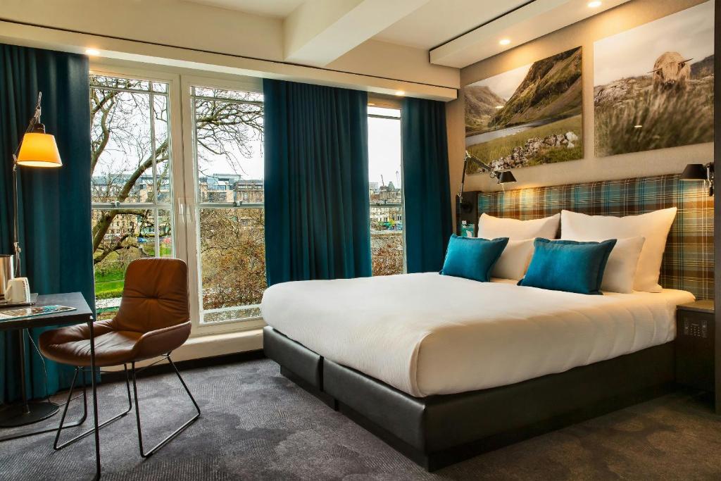 Quarto de hotel moderno com cama de casal e janela ampla no Motel One Edinburgh-Royal.