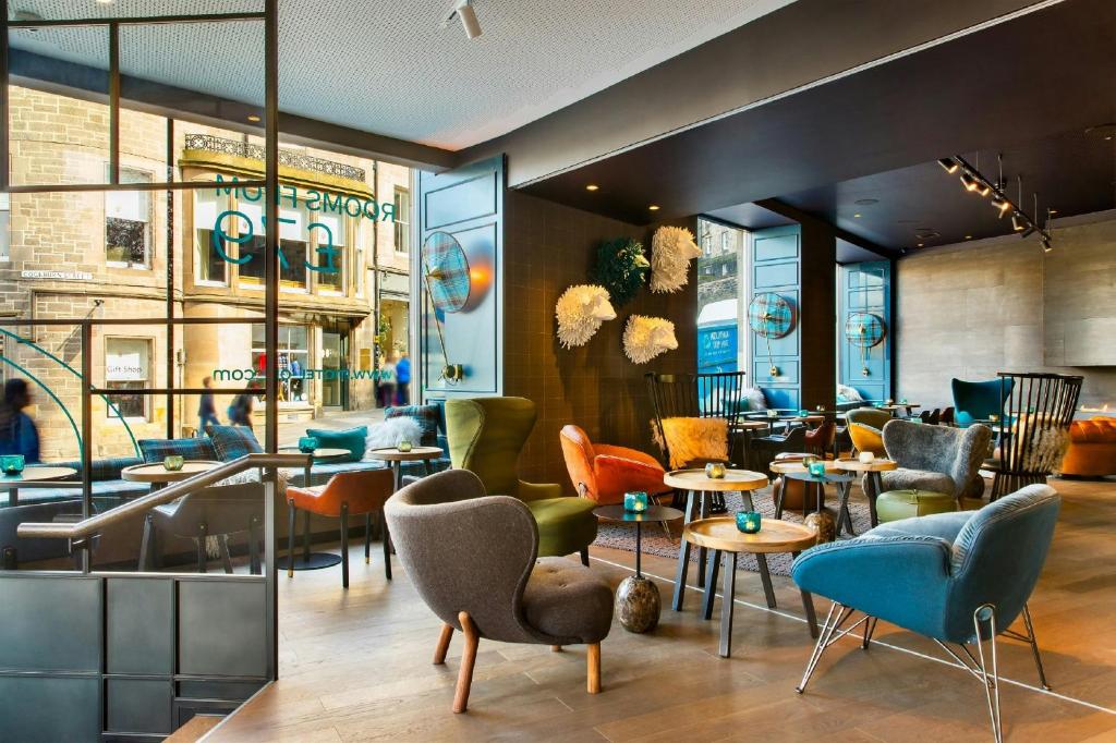 Lounge moderno e colorido com diversas poltronas e decoração estilizada no Motel One Edinburgh-Royal.