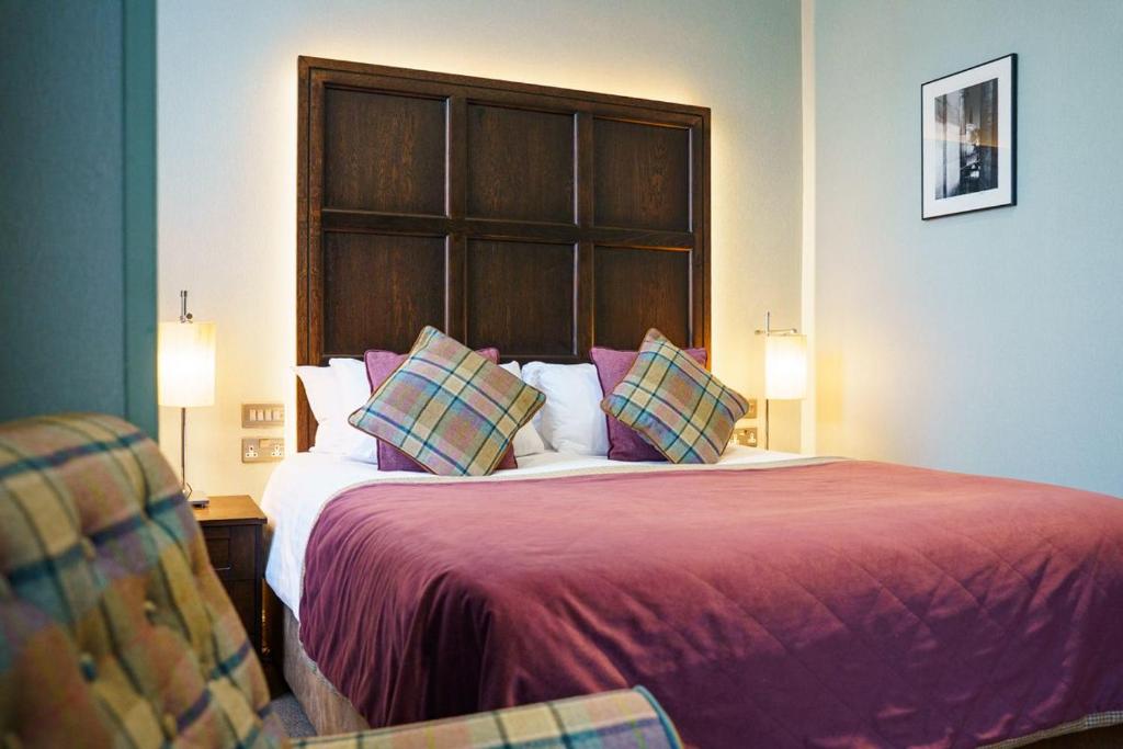 Cama de casal com colcha roxa e travesseiros xadrezes em quarto do The Parliament House Hotel.